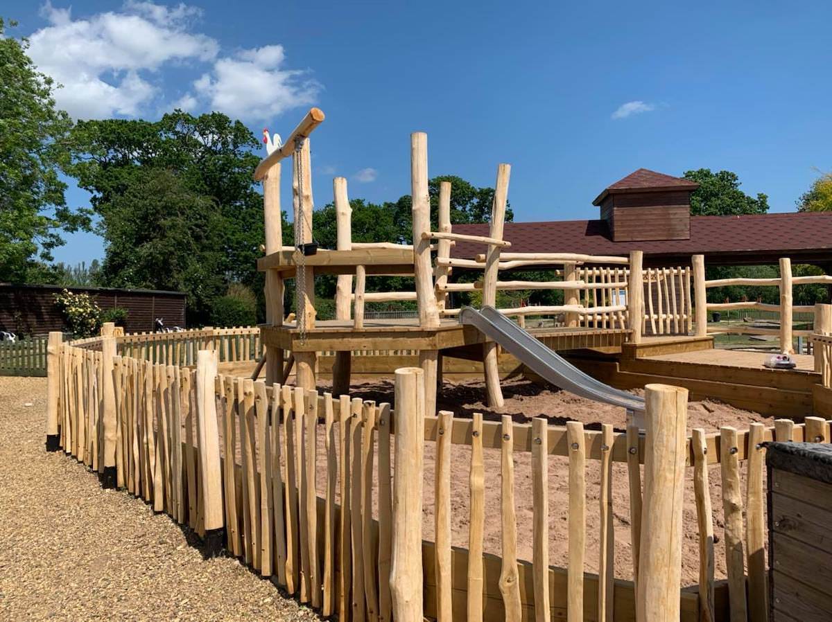 Fenced sand play area showing new material palette at Wroxham Barns
