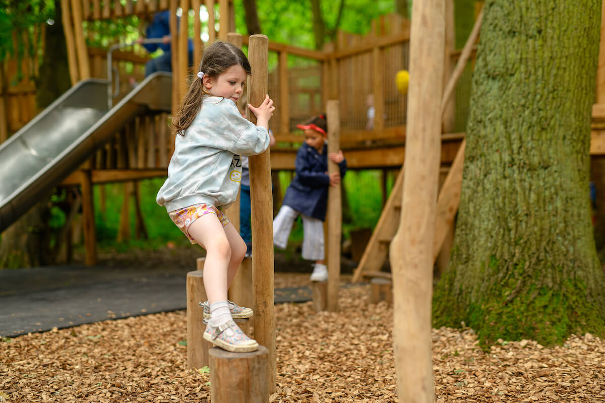 Clambering across the ground play at Hermits Hollow at Coombe Country Park with Adventure play by CAP.Co