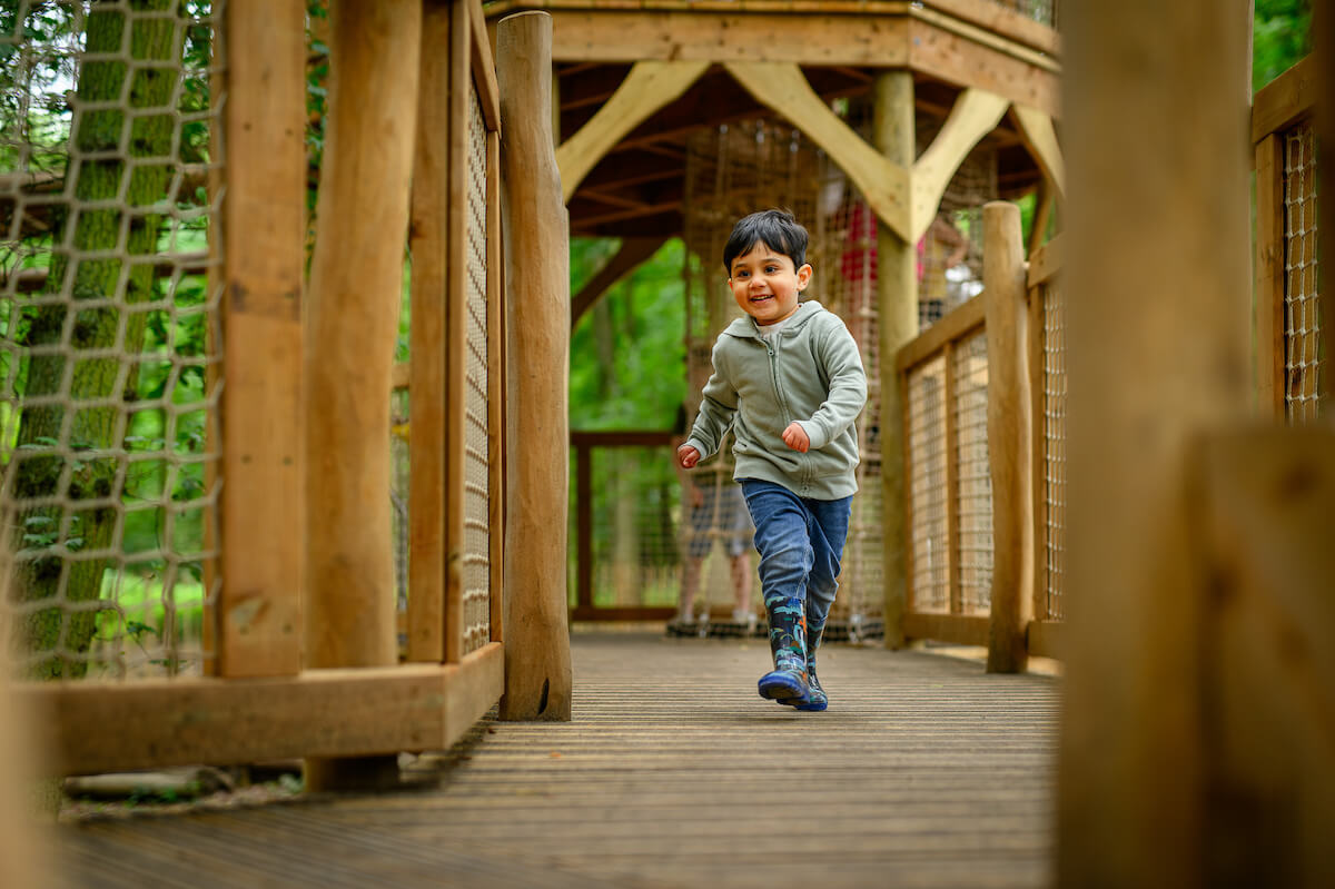 Running along the walk way at Hermits Hollow at Coombe Country Park with Adventure play by CAP.Co