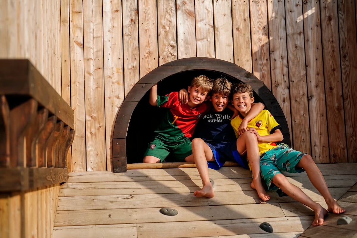 Three boys at the top of a sloped climbing wall at The Lost Garden within Blenheim Palace Adventure Play by CAP.Co