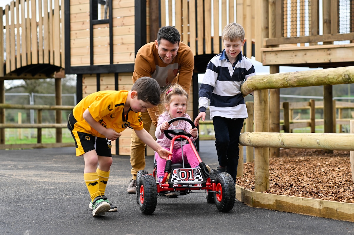 Family playing together on the cart track at Hockerhill Adventure Playbarn indoor and outdoor play in Staffordshire by CAP.CO