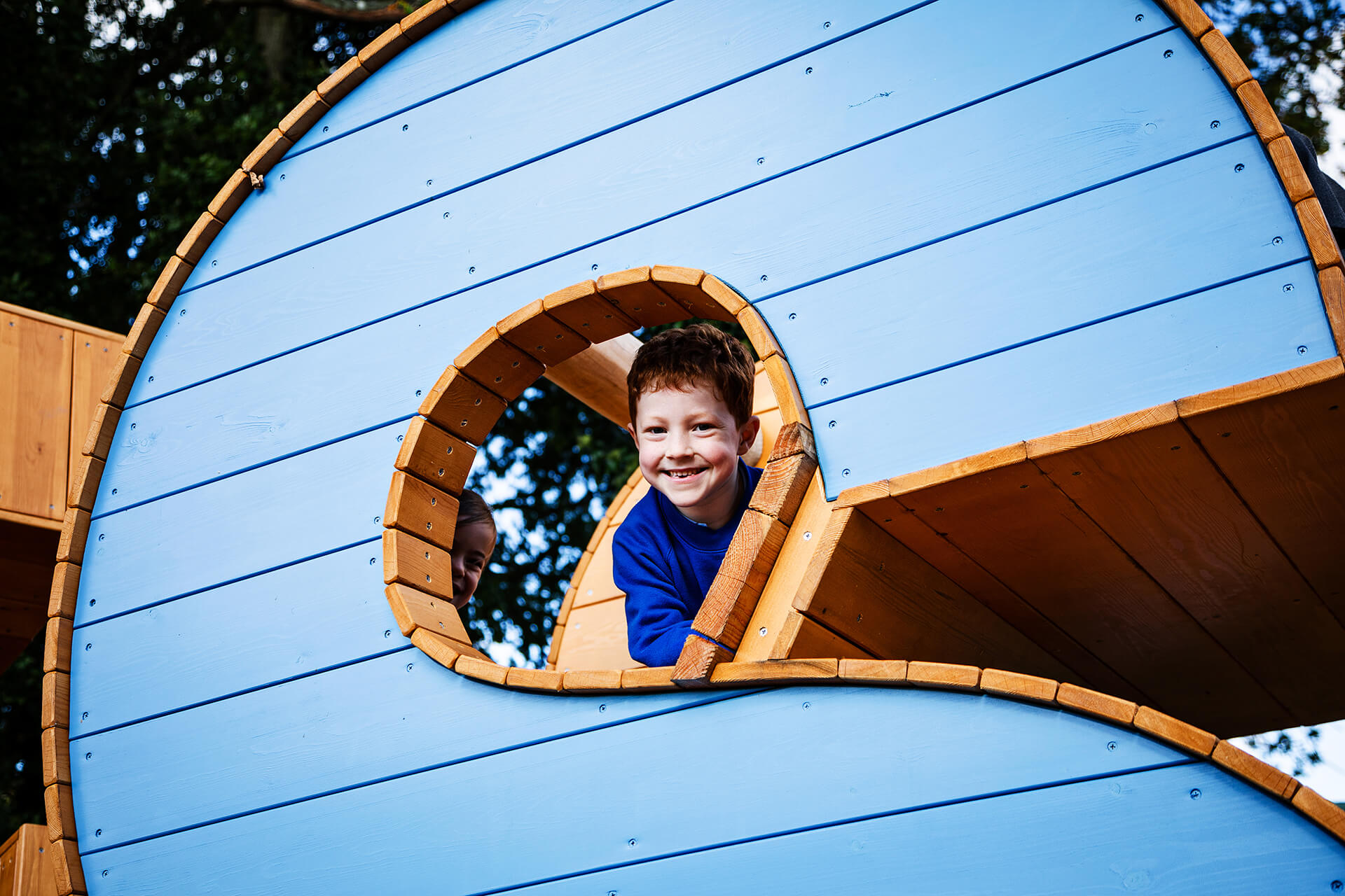A child smiling whilst playing at Poringland school built by CAP.CO photography by Kev Foster