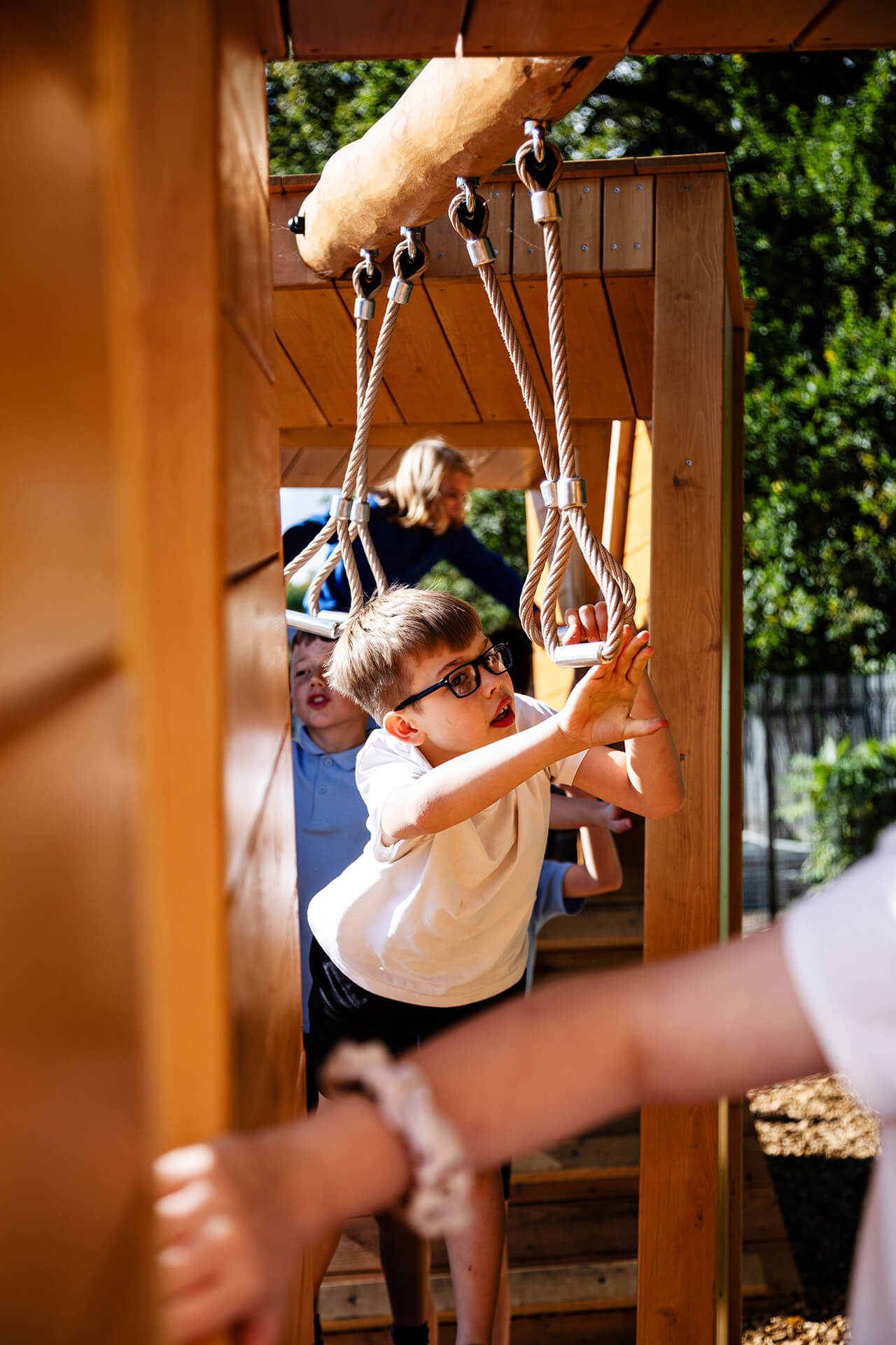 A child swinging on the rope fetaure at Poringland school playground built by CAP.CO photography by Kev Foster