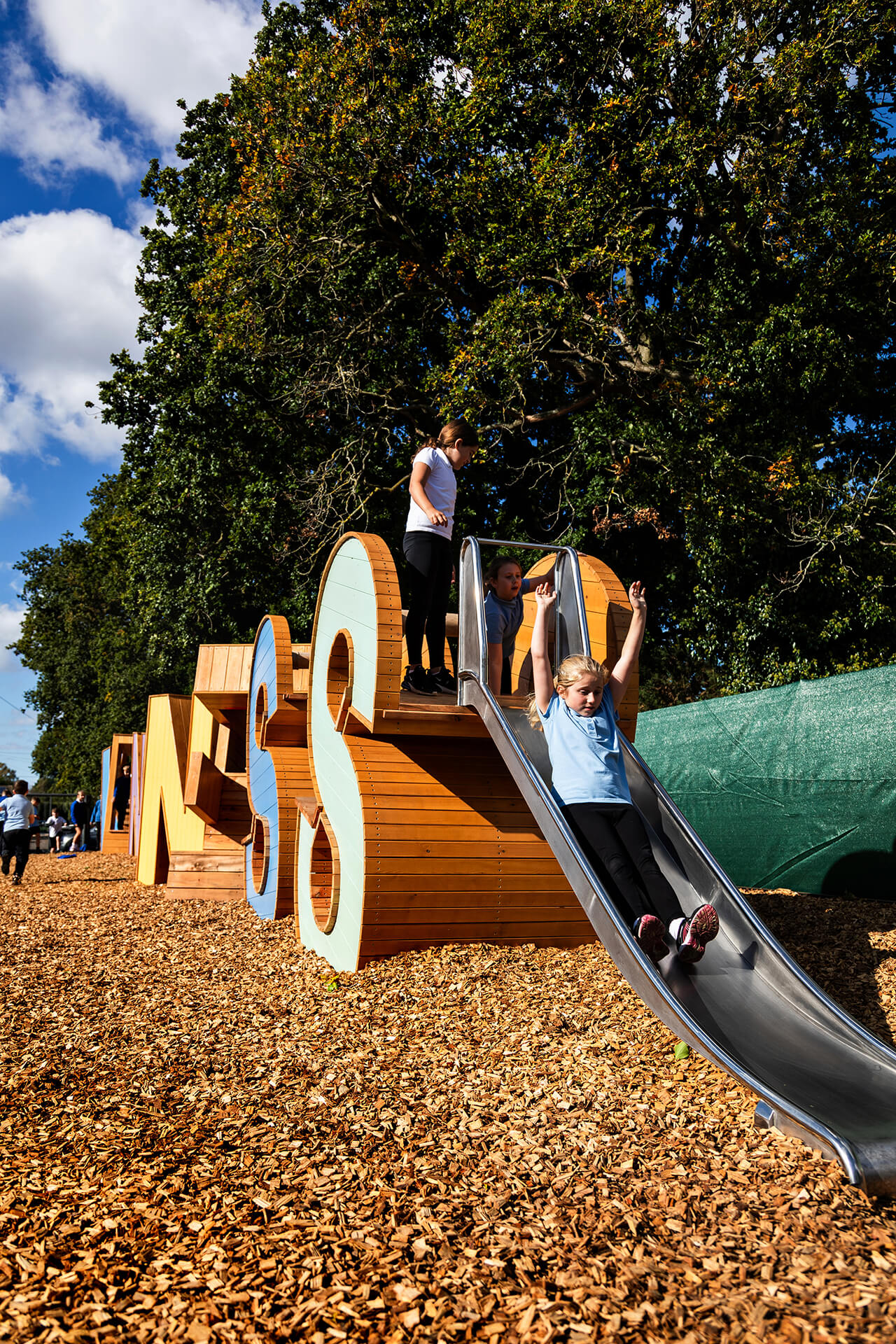 Child sliding down the slide on the CAPCO built Kindness playground at Poringland school photography by Kev Foster