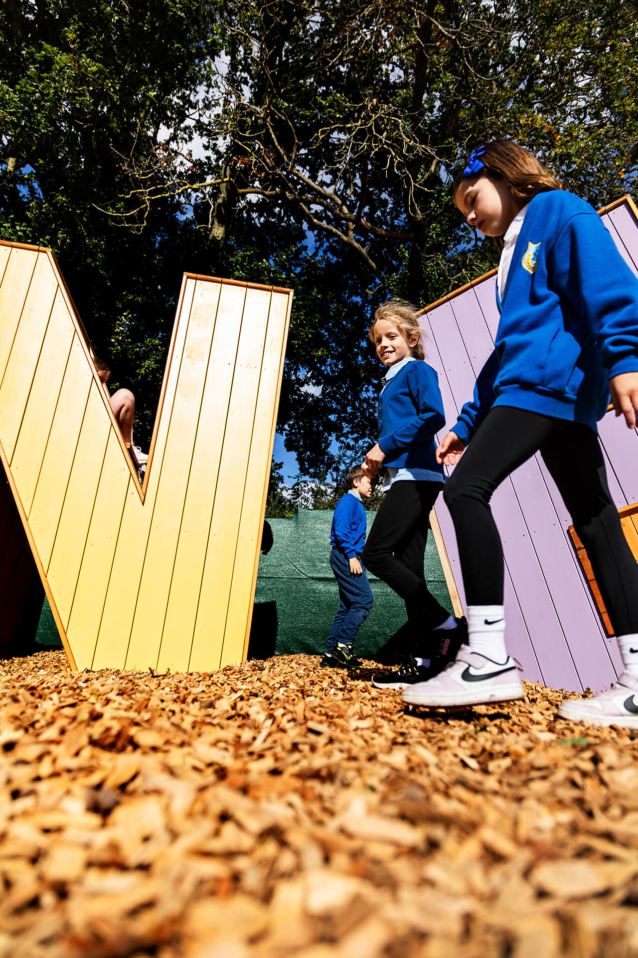 Children walking and talking past the letters at Poringland school built by CAP.CO photography by Kev Foster