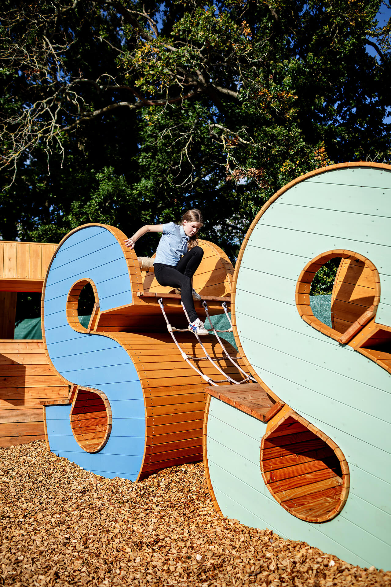 Poringland School Kindness playground built by CAPCO child climbing over the letters photography by Kev Foster
