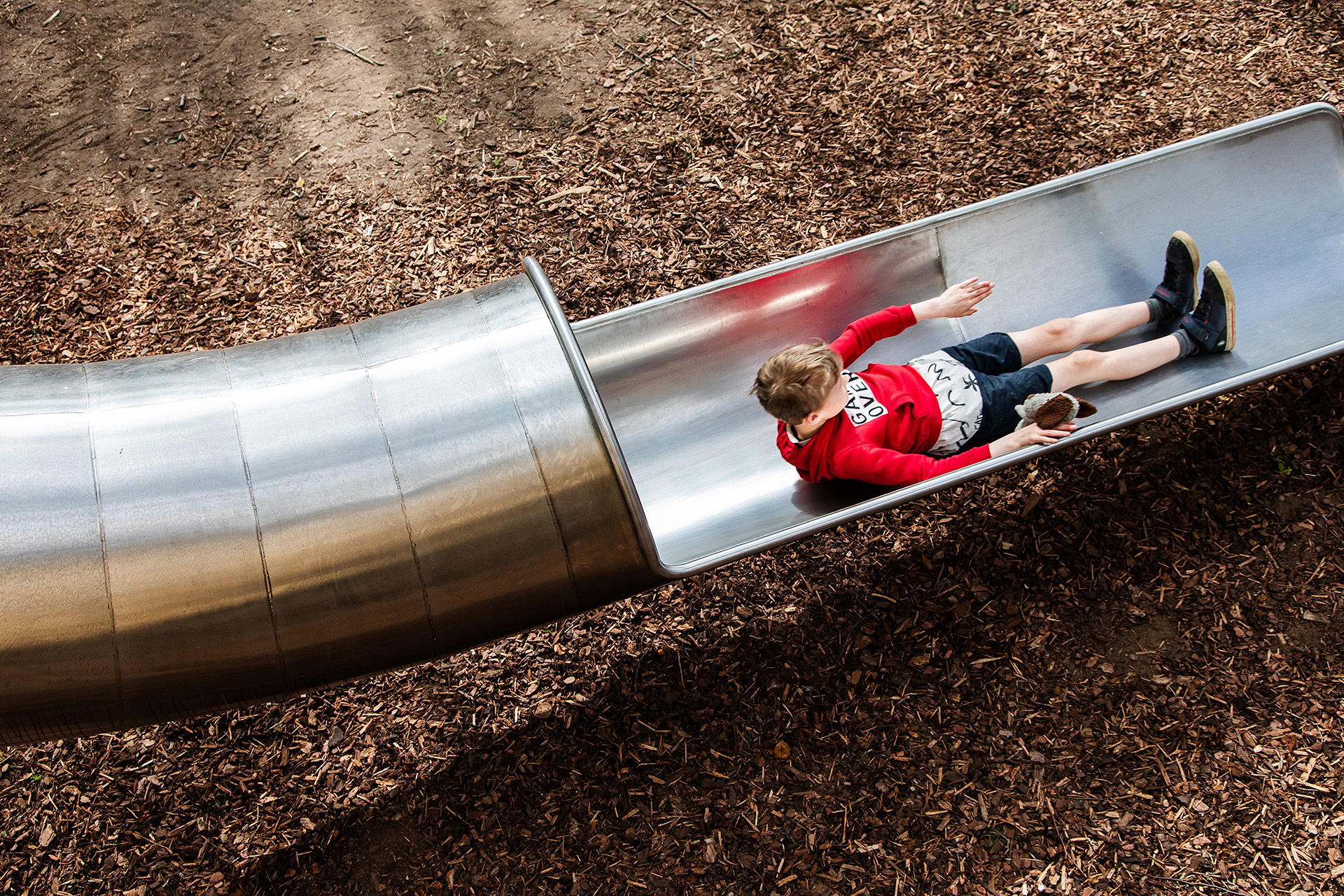 A boy flying down the fast tube slide at Woodland Adventures playground at The Belfry Hotel built and designed by CAP.CO photography by Kev Foster