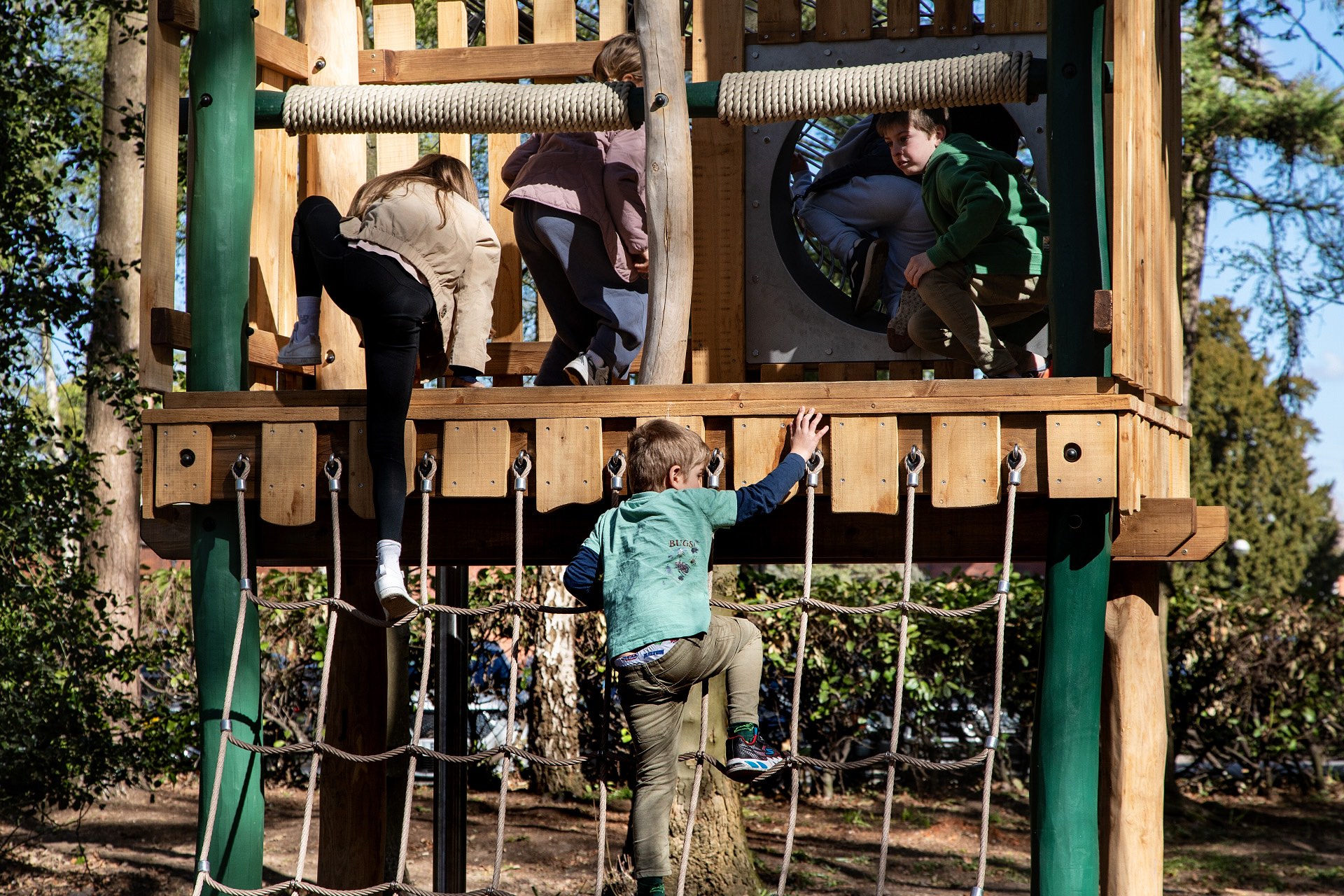 A little boy climbing up the cargo net at the Woodland Adventures playground at The Belfry Hotel built and designed by CAP.CO photography by Kev Foster