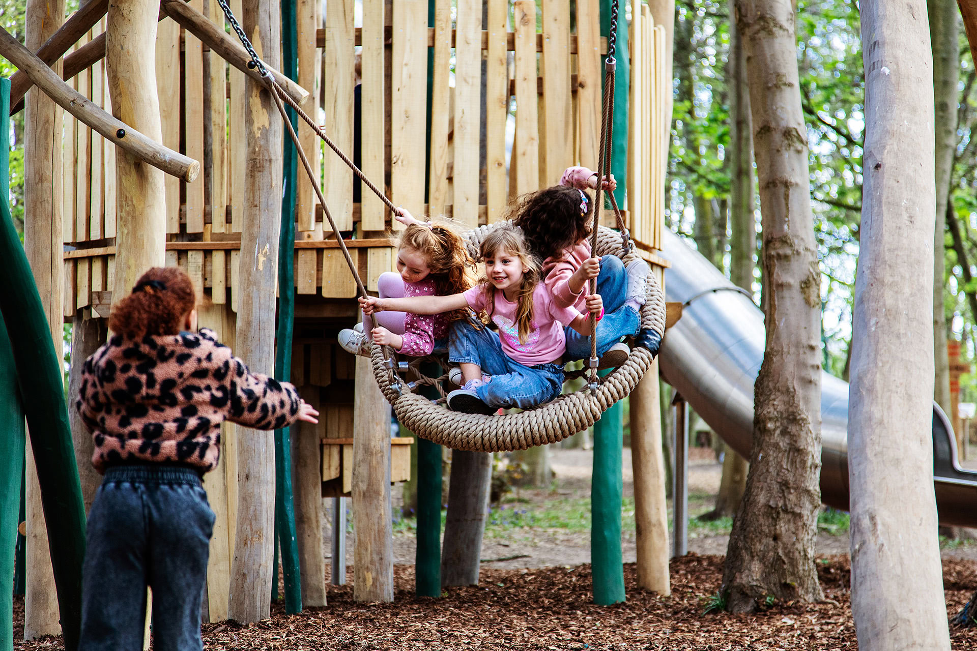 Children having fun whilst being pushed on the swing at the Woodland Adventures playground at The Belfry Hotel built and designed by CAP.CO photography by Kev Foster