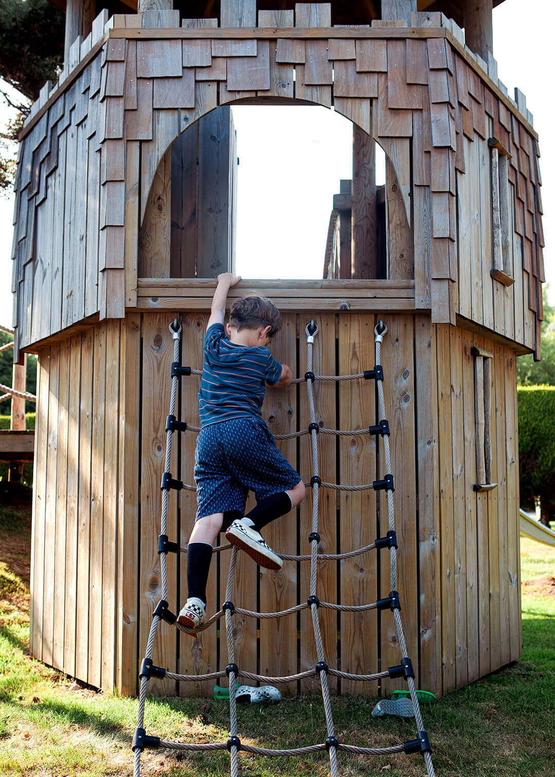 A boy climbing the cargo net at Scarborough Hill Country Inn Hotel pine tower playground built and designed by CAPCO photography by George Browne