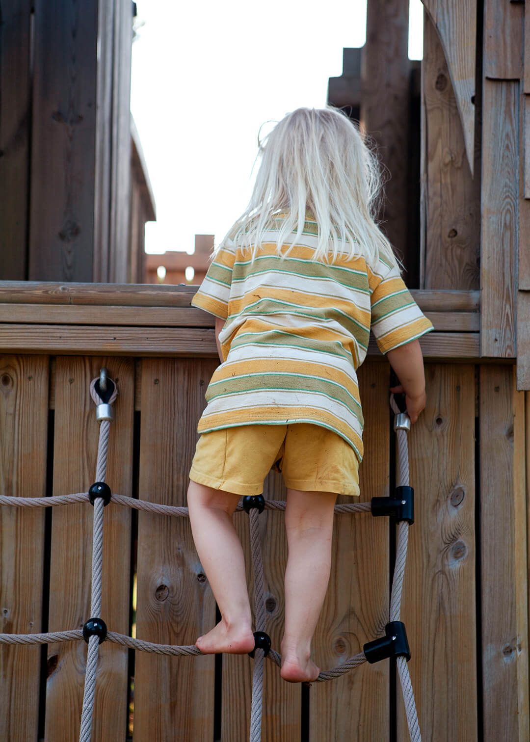 A little girl making it to the top of the cargo net at Scarborough Hill Country Inn Hotel pine tower playground built and designed by CAPCO photography by George Browne