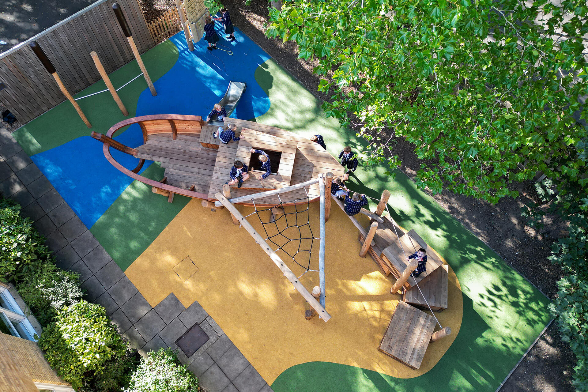 Aerial view of the Wherry Boat Yard school playground at Town Close School, Norwich, with wooden wherry, rope sail and cargo crates, designed and built by CAP.CO. Photography by George Browne
