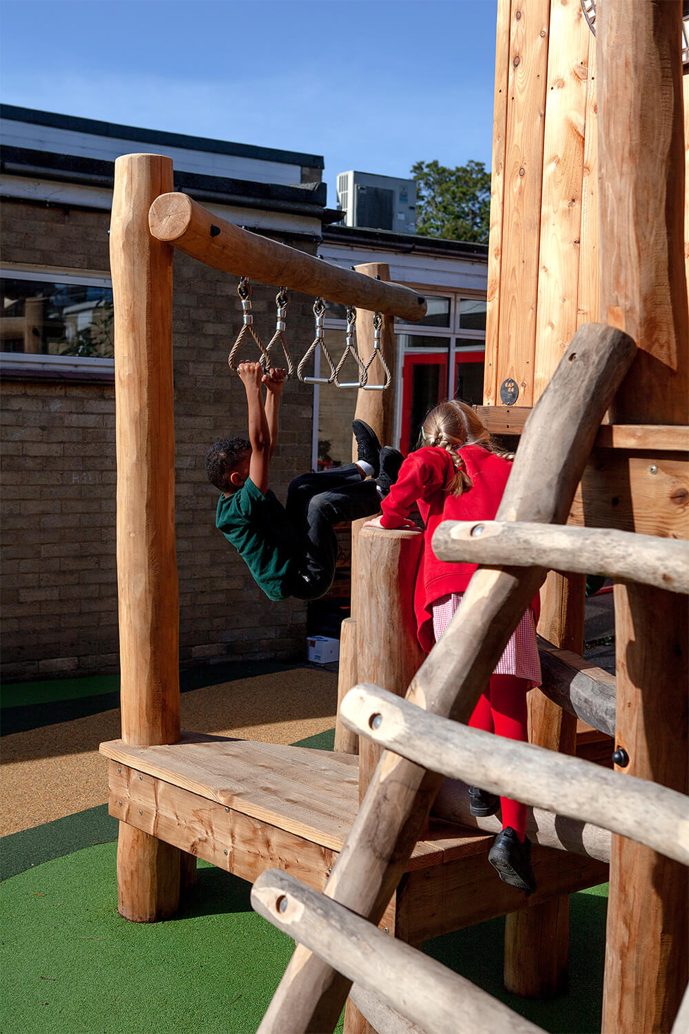 Children on the trapeze rings and log ladder of the play tower at Colman Infant School, Norwich, built by CAP.CO. Photography by George Browne