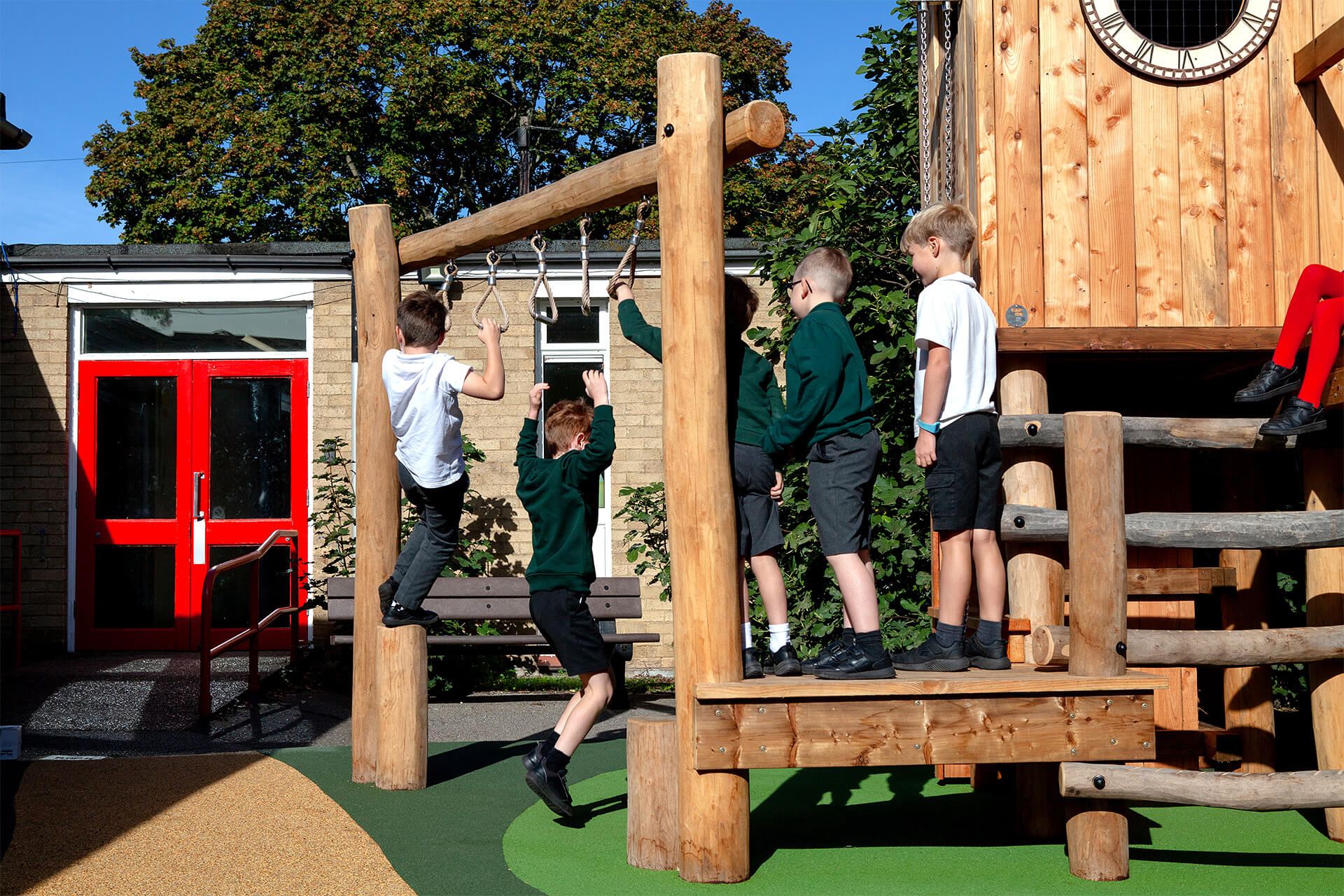 Children swinging on trapeze rings beside the play tower at Colman Infant School, designed by CAP.CO. Photography by George Browne
