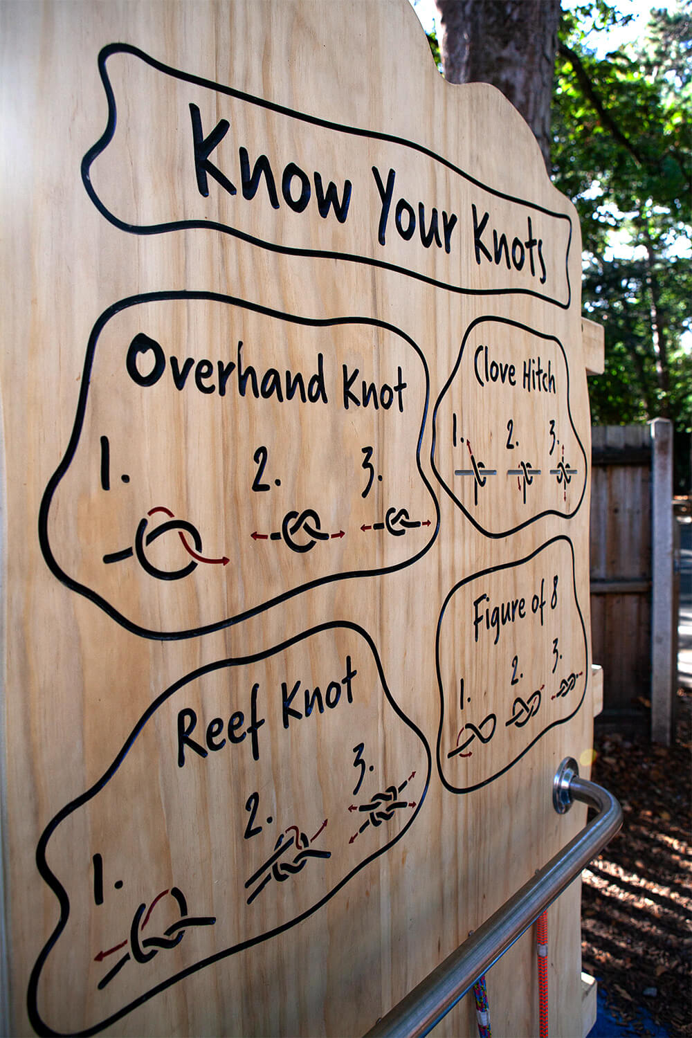 Close-up of the carved “Know Your Knots” board teaching children knot tying in a school playground at Town Close School, Norwich, by CAP.CO. Photography by George Browne