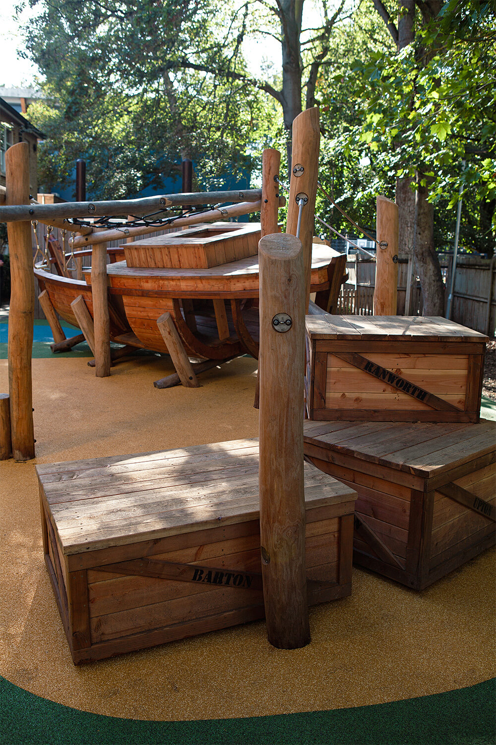 Timber cargo crates labelled with Norfolk place names beside the wherry boat in the Town Close School playground, designed by CAP.CO. Photography by George Browne