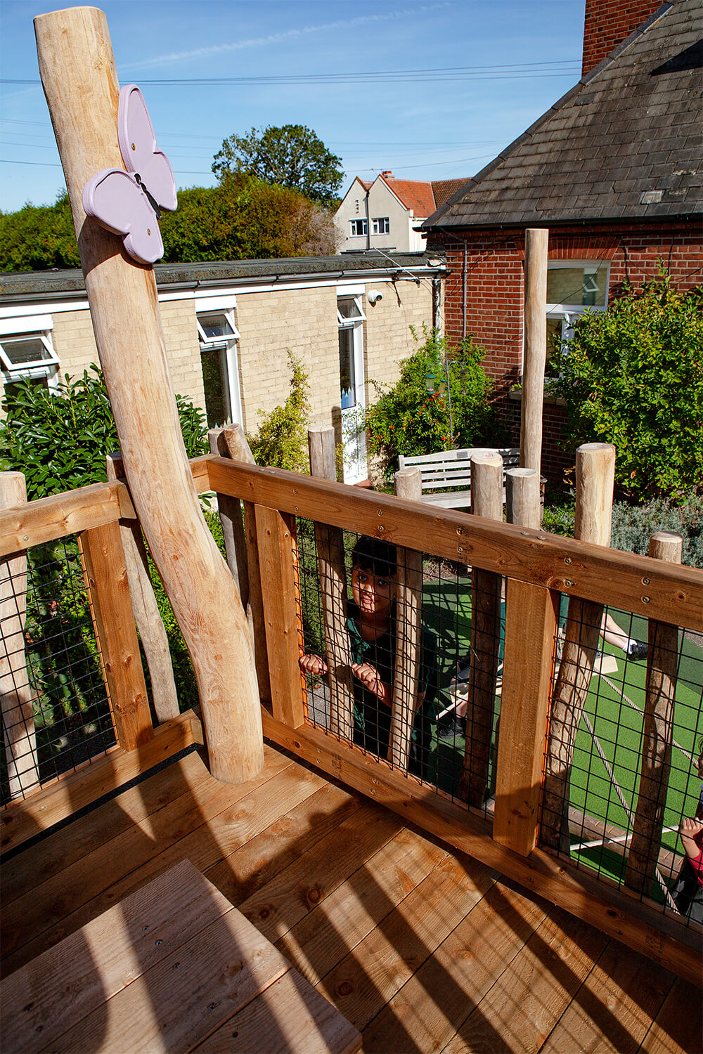 View from the top deck of the play tower through mesh and robinia posts at Colman Infant School, by CAP.CO. Photography by George Browne