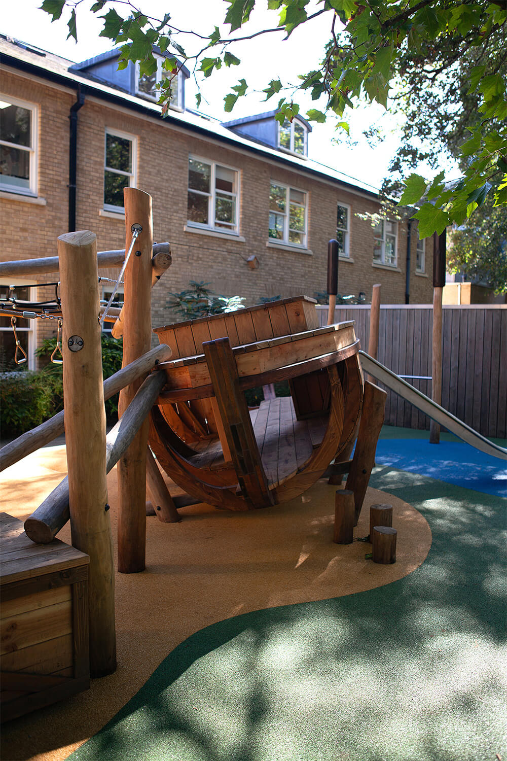 Wooden wherry boat play structure with curved larch hull and slide in a bespoke UK school playground at Town Close School, designed by CAP.CO. Photography by George Browne